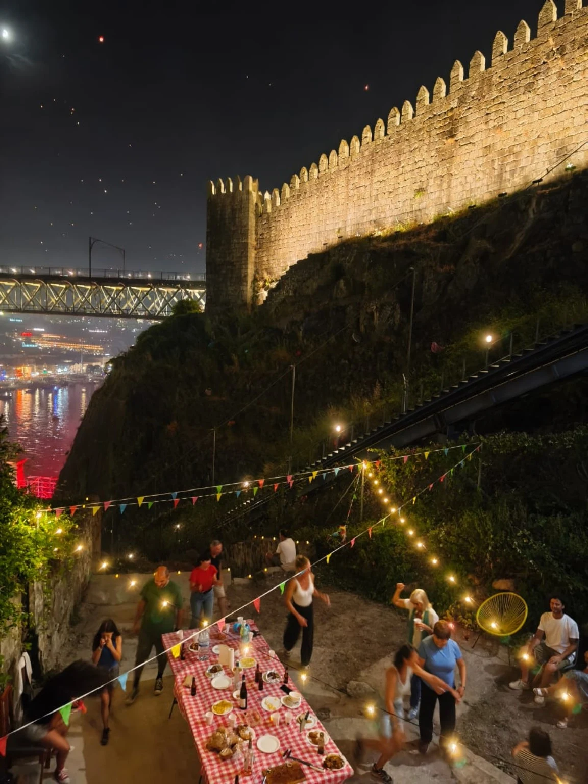 Encontro à noite com mesa partilhada junto à muralha iluminada